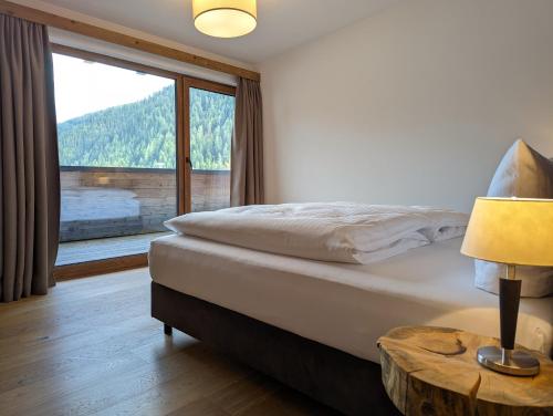 a bedroom with a bed and a large window at ARLhome Lodge - Zuhause am Arlberg in Sankt Anton am Arlberg