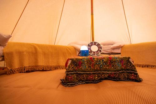 Una cama con una mesa con un reloj. en Avalon Boutique Camping @ The Crossways en North Wootton