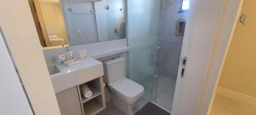 a bathroom with a toilet and a glass shower at Apartamento 2 suítes 200m da praia de Bombas in Bombas