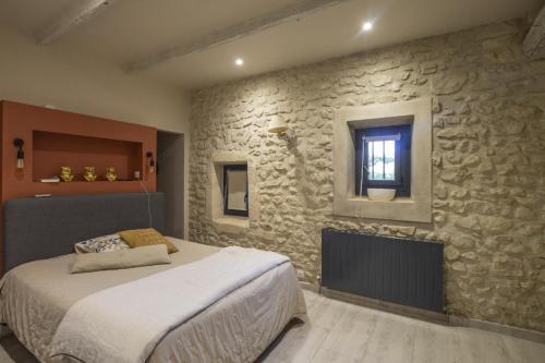 una camera con letto e parete in pietra di Le Mas de Laury a Châteaurenard