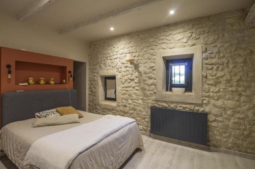 une chambre avec un lit et un mur en pierre dans l'établissement Le Mas des Oliviers, à Châteaurenard