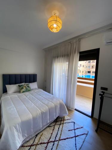 - une chambre avec un lit blanc et une fenêtre dans l'établissement Magnifique & élégant appartement, à Marrakech