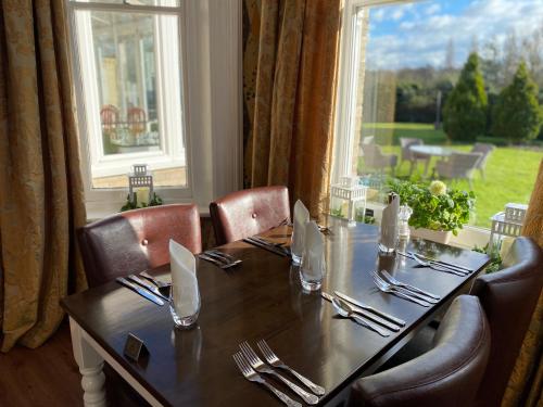 een eettafel met stoelen en een groot raam bij Broom Hall Country Hotel in Saham Toney