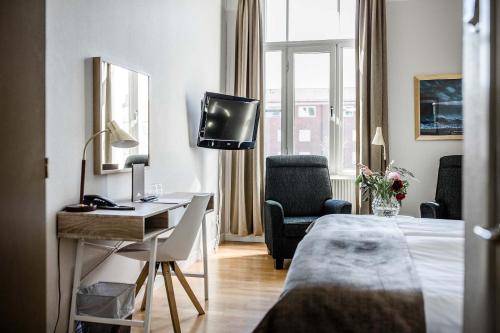 a hotel room with a bed and a desk and a television at Piteå Stadshotell in Piteå