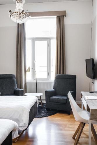 a bedroom with a bed and two chairs and a window at Piteå Stadshotell in Piteå
