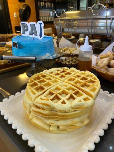 a waffle on a plate on a counter with a cake at Navega Beach Palace Hotel in Navegantes