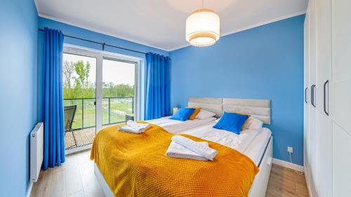 Dormitorio azul con cama y ventana grande en Baltic Nature Apartment & SPA en Dziwnów