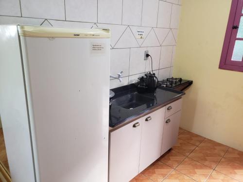 a kitchen with a sink and a white refrigerator at Pousada da Chacara in Nova Petrópolis