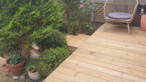a wooden deck with a chair and some plants at House on Costal Village in Peacehaven