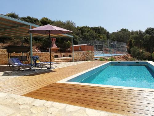 a swimming pool with a wooden deck and an umbrella at Villa VaKo in Vathí