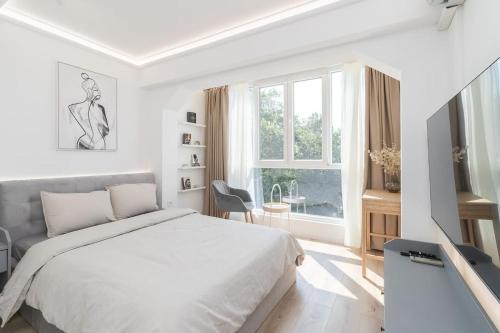a white bedroom with a bed and a window at Apartment Cinderella in Varna City