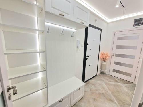 a white kitchen with white shelves and a door at Apartment Cinderella in Varna City