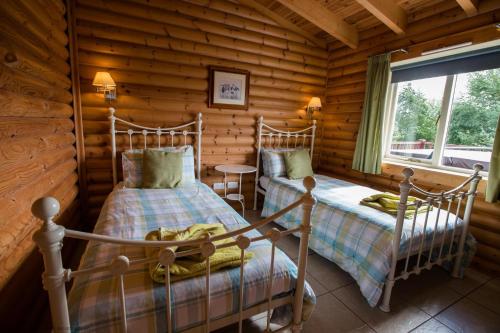 una camera con 2 letti in una baita di tronchi di Mallard Lodge a Selby