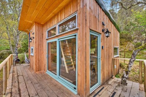a wooden house with glass doors on a deck at Finest Retreats - Cosagach Falls Cabin in Kiltarlty