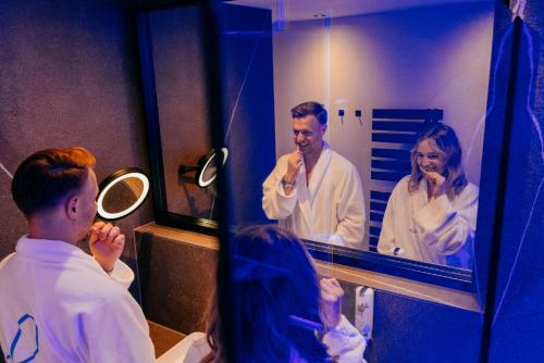 a man and woman brushing their teeth in front of a mirror at Aqua Blu Hotel in Bad Füssing