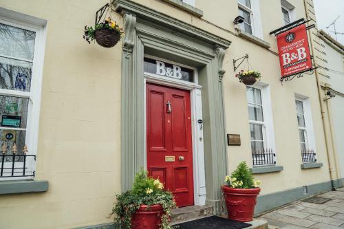 a red door on a building with potted plants at Charlemont House in Dungannon