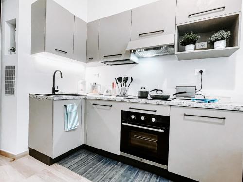 una cocina con armarios blancos y horno negro en MYHOUSE INN 500 - Affitti Brevi Italia, en Turín