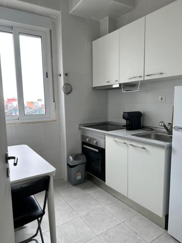 Una cocina con gabinetes blancos y un fregadero y una ventana. en Vicky Porto, en Oporto