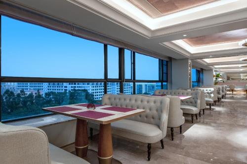 a dining room with chairs and a table and large windows at Mercure Guangzhou Baiyun International Airport - Airport Free Shuttle Bus in Huadu