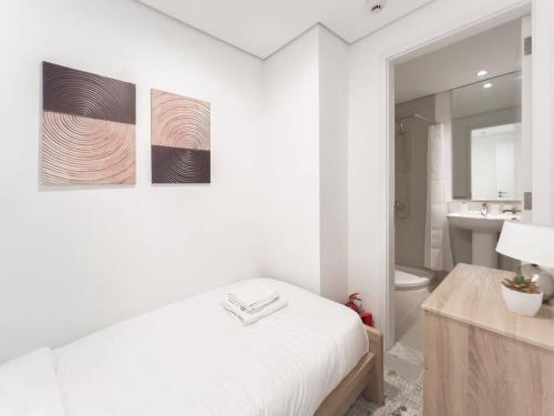 a white bedroom with a bed and a bathroom at StoneTree - Spacious 3 BR in The Pulse C2 in Dubai