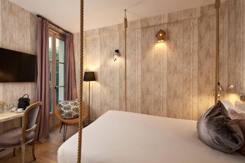 a bedroom with a swinging bed and a desk at Les Plumes Hotel in Paris