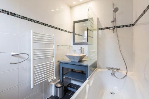 a white bathroom with a tub and a sink at Les Aiguilles De Warens in Combloux