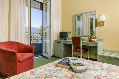 ストレーザにあるHotel Lido La Perla Neraのベッド、デスク、椅子が備わる客室です。