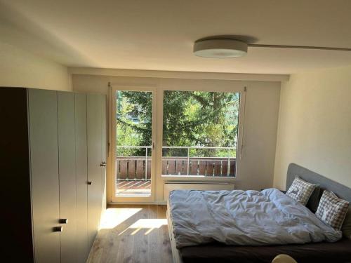 een slaapkamer met een bed en een groot raam bij Golfresidenz Davos Platz in Davos