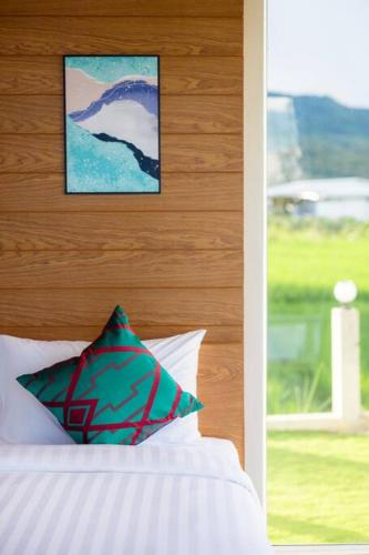 a bed with a pillow and a picture on the wall at Vann House Chiang Rai- near Mae Fah Luang University in Chiang Rai