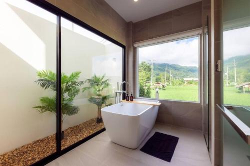 a bathroom with a bath tub and a large window at Vann House Chiang Rai- near Mae Fah Luang University in Chiang Rai
