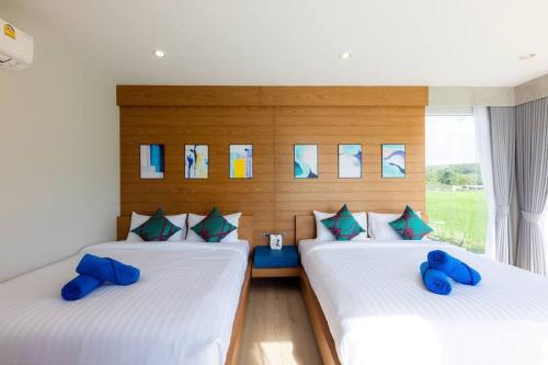 two beds in a room with blue pillows at Vann House Chiang Rai- near Mae Fah Luang University in Chiang Rai