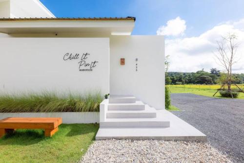 a white house with a staircase and a bench at Vann House Chiang Rai- near Mae Fah Luang University in Chiang Rai
