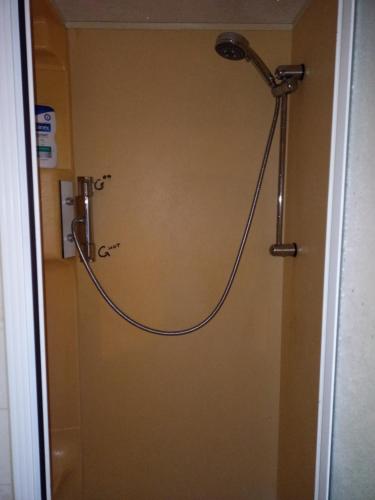 a shower with a hose hooked up to a wall at De Boerenskuur..chalet.. in Assendelft