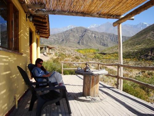 a man sitting in a chair on a porch with a table at Las Margaritas in Potrerillos