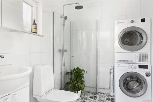 a bathroom with a shower and a washing machine at Charming apartment in a red house in Stockholm in Stockholm