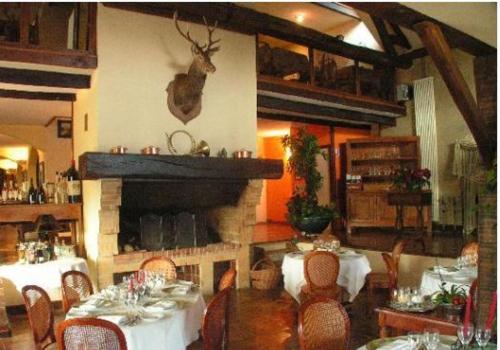 a dining room with tables and chairs and a fireplace at Les Etangs de Guibert in Neufchâtel-en-Saosnois