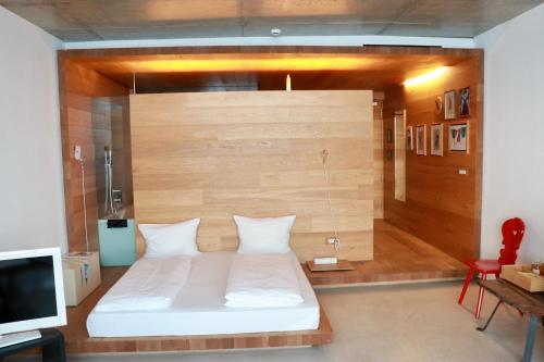 - une chambre avec un lit blanc et un mur en bois dans l'établissement Living Kampill, à Bolzano