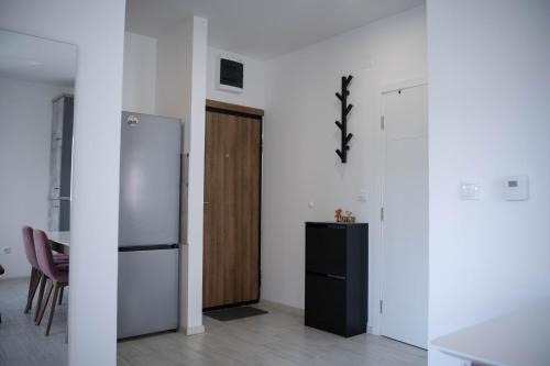 a white kitchen with a refrigerator and a table at Apartman Arija in Ruma
