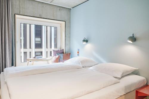 a large white bed in a room with a window at Villa Viva - ein Haus das Brunnen baut in Hamburg