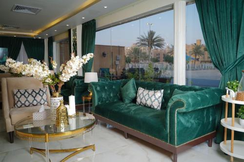 a living room with a green couch and a glass table at قمة نجد للشقق الفندقيه in Al Khobar