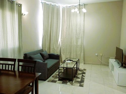 a living room with a couch and a table at Marbella Holiday Homes - Al Nahda 1BHK in Dubai