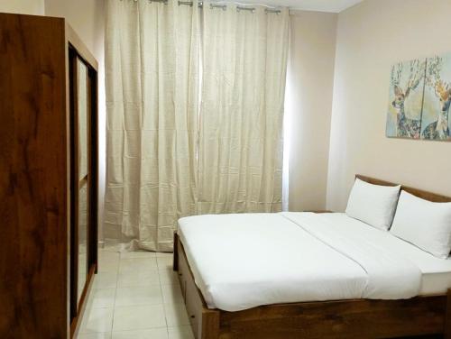 a white bed in a room with a window at Marbella Holiday Homes - Al Nahda 1BHK in Dubai