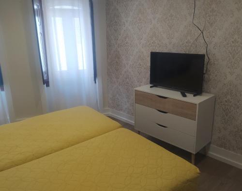 a bedroom with two beds and a tv on a dresser at Mondalva Guesthouse in São Pedro de Alva