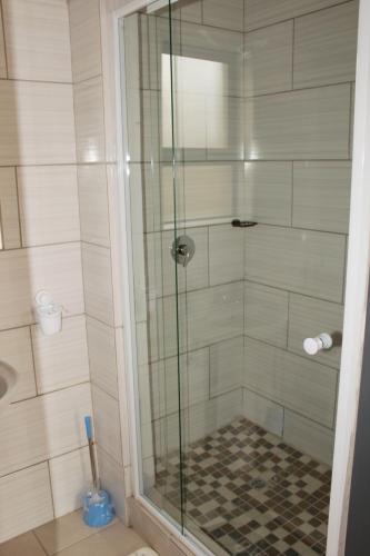 a shower with a glass door in a bathroom at EMPEROR LODGE AND TOURS in Germiston