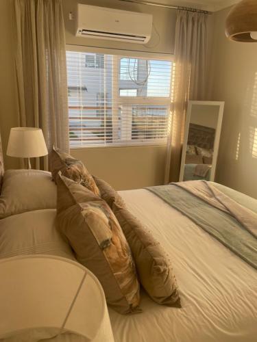 a bedroom with a bed with pillows and a window at De Santa Villas in St Helena Bay