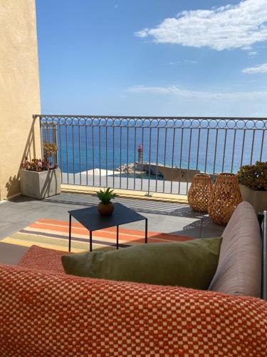 a couch on a balcony with a view of the ocean at Hôtel Des Gouverneurs in Bastia