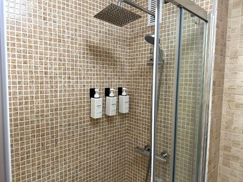 a shower with three shampoo bottles on a tiled wall at Santa Pola port, sea view in Santa Pola