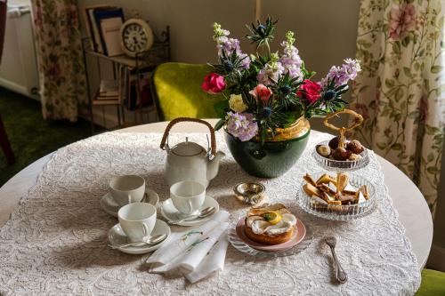 a table with a tea set with a vase of flowers at Pension Landhaus- Frühstückspension im Brombachtal in Brombachtal