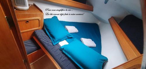 un piccolo letto in una piccola barca con cuscini blu di Super Castor - Dormir sur un grand voilier 6 personnes By Nuits au Port a La Rochelle