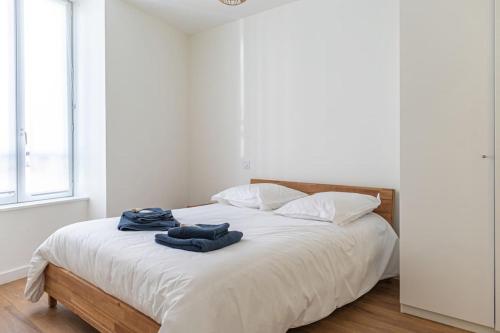 - un lit blanc avec 2 serviettes bleues dans l'établissement Joli T2 Champagne au Mont d'or, à Champagne-au-Mont-dʼOr